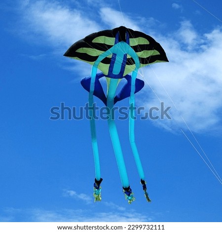 A single multicolor rainbow colorful handmade DIY kite flies isolated in the blue sky. Concept of freedom