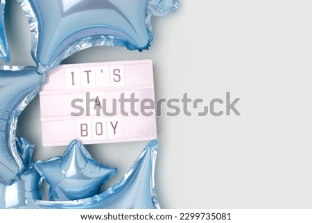 It's a boy. Lightbox with letters and inflatable foil balloons in a blue color. Baby shower festive concept with place for text. 