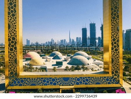 Dubai skyline seen through the large golden frame with nearby park and Dubai skyline aerial cityscape view of the Emirate