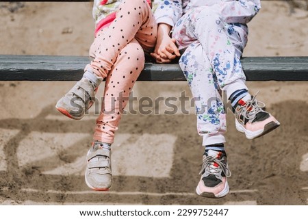 Two little girls best friends, children, sisters sit on a wooden bench in the park outdoors. Photography, close-up portrait, friendship.
