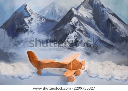 background texture empty space for baby with wooden plane, white clouds and beautiful, snowy mountains in the background. Celebratory background design for birthday celebration. 