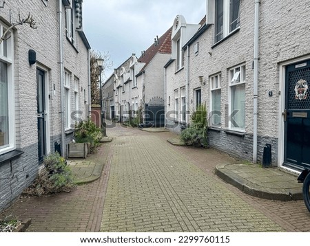 Gouda, Netherlands - April 1, 2023: Quaint houses and shoppes along the streets with the Gouwekerk Steeple in the background, in Gouda, Netherlands
