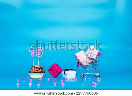 Creative card Happy birthday background for a girl or woman with a number of candles in a muffin pie  16. Happy birthday gift boxes in pink shades. Background copy space anniversary on blue background