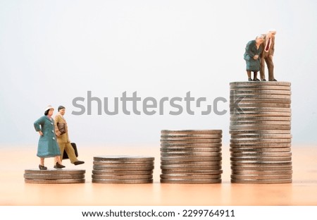 Miniature figure young man and woman walk and Couple Senior Pensioners standing on the top coins stacking for wealth financial planning ,money saving and life insurance of retirement concept.  Royalty-Free Stock Photo #2299764911
