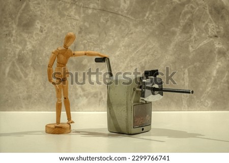 A photo of a Mannequin using an old mechanical pencil sharpener