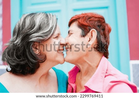 Senior gay lesbian couple kissing outside - LGBTQ aged tourists having tender moment during summer vacation Royalty-Free Stock Photo #2299769411