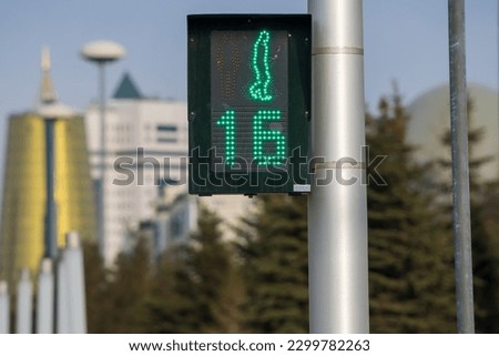 Traffic light located within the city limits shows a green permissive signal for crosswalk traffic. The time timer shows the remaining crossing time of 16 seconds