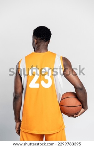 Back view of basketball player wearing basketball uniform, holding ball isolated on white background. Sport concept Royalty-Free Stock Photo #2299783395