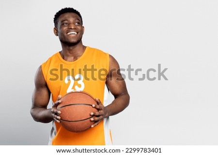 Handsome smiling African American man playing basketball, catching ball looking away, isolated on white background, copy space. Sport competition concept  Royalty-Free Stock Photo #2299783401