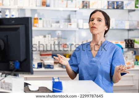 Positive female pharmacist standing behind counter in drugstore