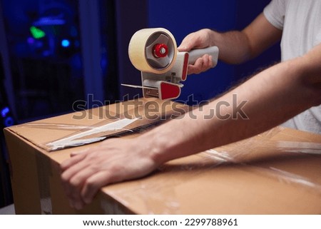 young man packing a monitor in a cardboard box Royalty-Free Stock Photo #2299788961