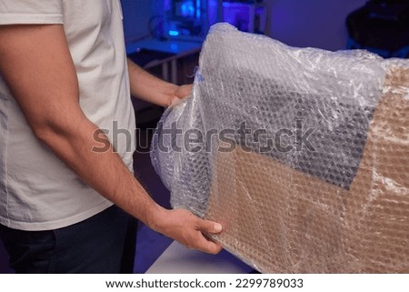 young man packing a monitor in a cardboard box Royalty-Free Stock Photo #2299789033