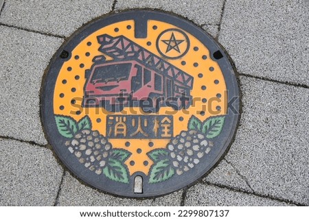 A metal cover of fire hydrant in the basement. The metal cover features a fire engine and hydrangeas.