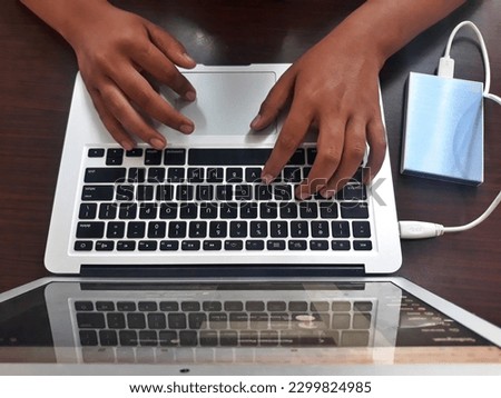 Hand typing use Laptop transferring data in external hard drive storage with smart phone background at office work place. Selective focus