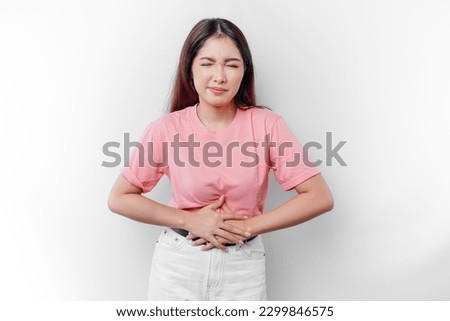 An Asian woman is hungry or having menstruation or stomach ache and touching her belly  Royalty-Free Stock Photo #2299846575