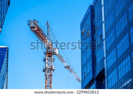 Construction of new high-rise buildings using a tower crane. Royalty-Free Stock Photo #2299852813