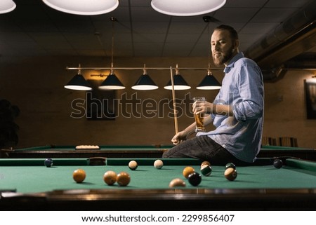 Young caucasian man drinking beer near pool table in bar. Copy space Royalty-Free Stock Photo #2299856407