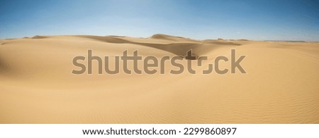 Landscape scenic view of desolate barren western desert in Egypt with large sand dunes against blue sky background Royalty-Free Stock Photo #2299860897