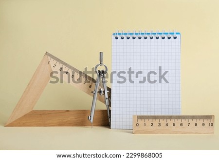 Triangle, notebook, protractor and compass on yellow background