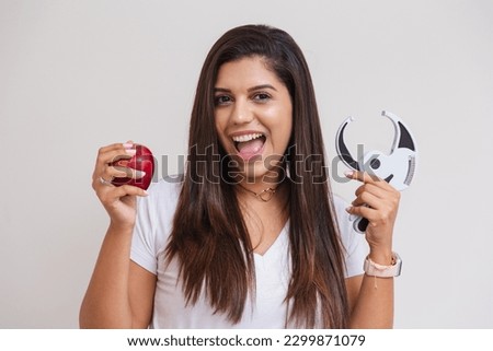 Beautiful Brazilian woman, nutritionist, weight loss, white shirt and pink pants. advertising photo, apple and adipometer.