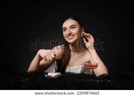Fashionable photo of attractive young woman lighting candle on her Birthday cake against black background