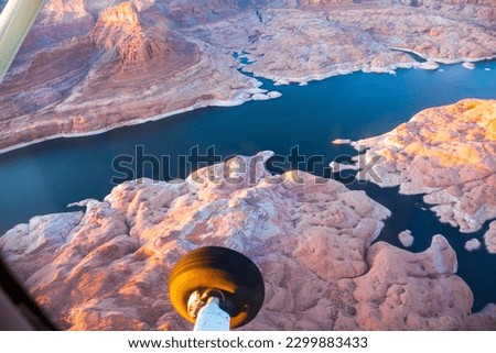 U.S. Landscape under the wing of an airplane. The coast of Lake Powell is cut by narrow canyons. Grandiose huge lake of artificial origin among the picturesque red sandstone cliffs. 