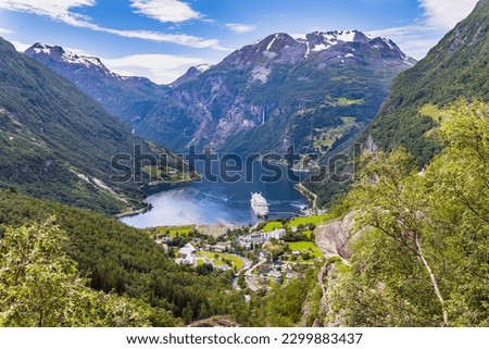 The largest, most beautiful and famous Norwegian fjord Geiranger. Snow-white ocean liner is moored at the pier. Warm sunny day in July. Summer trip to Norway. Royalty-Free Stock Photo #2299883437