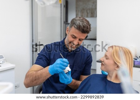 Dentist showing dental plaster mold to the patient. Dentist doctor showing jaw model at dental clinic, dental care concept. Dental care concept. Royalty-Free Stock Photo #2299892839