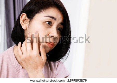 Asian Woman Checking Her Dark Eye Circles and Wrinkles skin in the Mirror