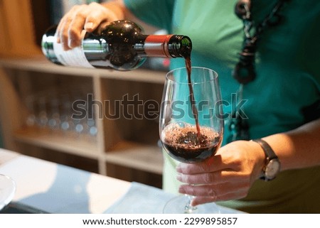 Woman pooring glass of red wine  Royalty-Free Stock Photo #2299895857