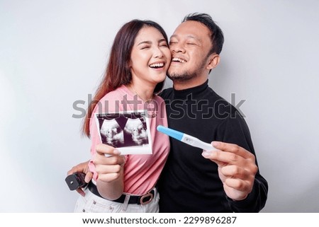 Happy family concept. Married couple bonding and holding positive pregnancy test and ultrasound picture
