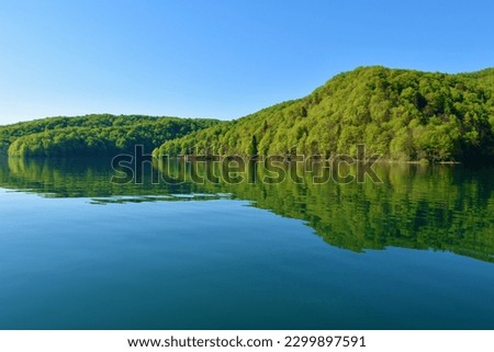 Forest covered hills above Kozjak lake and a reflection in the water at Plitvice lakes in Lika-Senj county, Croatia  Royalty-Free Stock Photo #2299897591