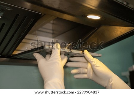 Someone hands trying to removing a filters from cooker hood for cleaning it. Clean your filters every two to three months, depending on your cooking habits. Royalty-Free Stock Photo #2299904837