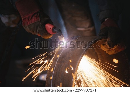 Welder cuts a metal pipe with a plasma cutter close up. Royalty-Free Stock Photo #2299907171