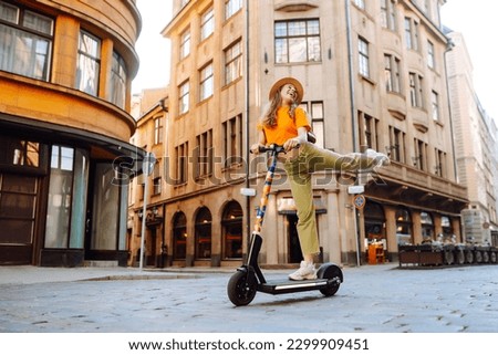 Young woman driving electric scooter through the city. Active life. Ecological transportation concept. Royalty-Free Stock Photo #2299909451