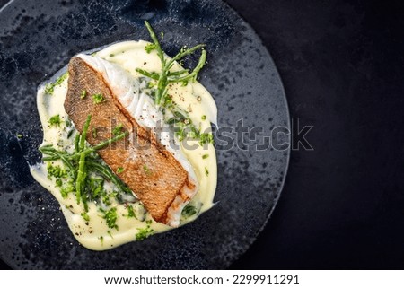 Modern style traditional fried skrei cod fish filet with mashed potatoes and glasswort served as top view on ceramic design plate with copy space right
