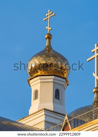 Gilded dome with a cross of an Orthodox church against a blue clear sky. Golden church dome on blue background