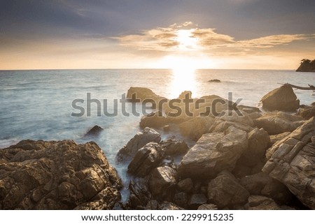 Beautiful blazing sunset landscape in the sea and orange sky above it with awesome sun golden reflection on calm waves as a background. Amazing summer sunset view on the beach in Thailand