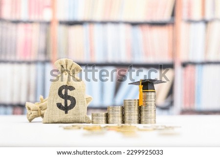 Tuition payment or tuition fee, expense for graduate study abroad program concept : Black graduation cap on stacks of coins, depicting fees charged by education institution for instruction or services Royalty-Free Stock Photo #2299925033