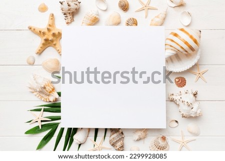 Summer time concept with blank greeting card and blank white paper on colored background. Seashells from ocean shore in the shape of frame separated with space for text top view.
