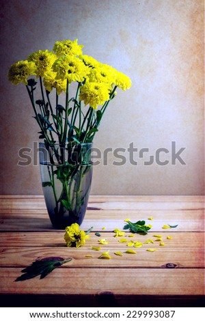 Still life with yellow flowers on wooden table over grunge background