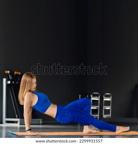 Side view portrait of attractive young woman doing exercises on rubber mat
