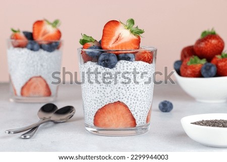 Chia pudding with strawberries and blueberries, chia seeds on a pink background. Healthy breakfast concept.  Royalty-Free Stock Photo #2299944003