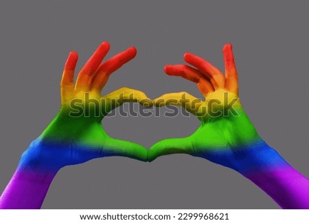 Human hands with rainbow light on it showing heart shape over grey background. Freedom of love, choice, support. Concept of freedom, lgbt, choice, human relation, community, togetherness, symbolism