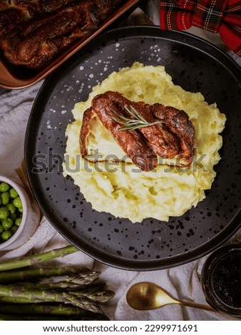 Toad in the Hole on a Black Plate with Mashed Potatoes