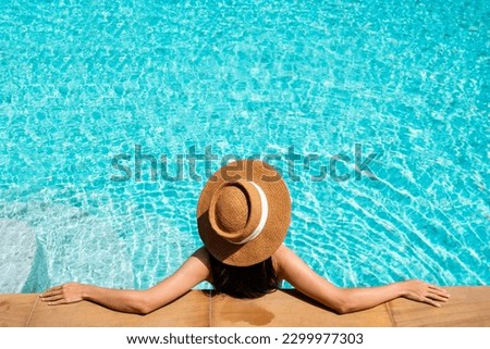 Asian woman in swimwear relaxing in swimming pool during her summer holiday leisure time at luxury hotel. Copy space, top view. Summer and vacation concept