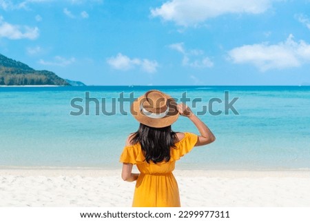 Happy traveler Asian woman on yellow dress relax on the tropical sandy beach. Summer, holiday concept. Copy space Royalty-Free Stock Photo #2299977311