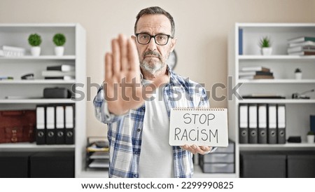 Middle age man business worker holding stop racism notebook at office