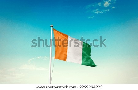 Waving flag of  Ivory Coast in beautiful sky.  Ivory Coast flag for independence day. Royalty-Free Stock Photo #2299994223