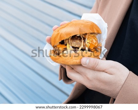 burger with 2 cutlets holding a man